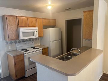 Killeen apartment for rent - A kitchen with a white refrigerator, white stove, and white microwave.