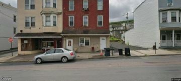 Ashland apartment for rent - A car is parked in front of a building with a red brick facade.