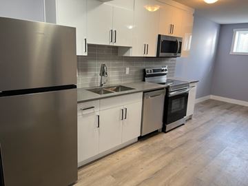 Edmonton apartment for rent - A modern kitchen with a stainless steel refrigerator and white cabinets.