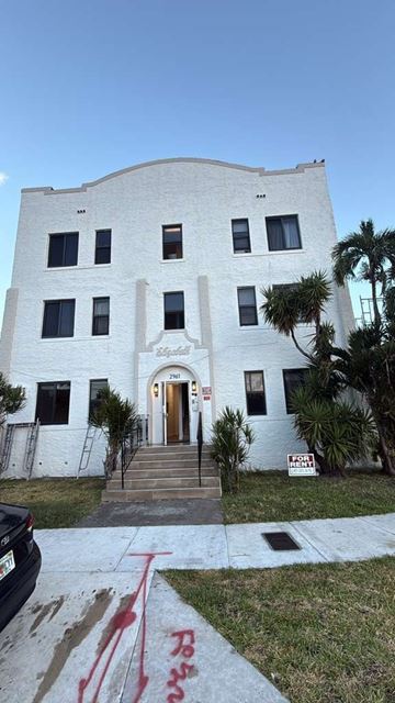 Miami apartment for rent - A white building with a red graffiti on the ground in front.