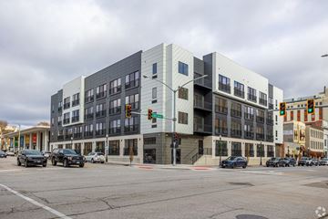Davenport apartment for rent - A modern building with a grey and white facade is situated on a street corner with cars parked in front.