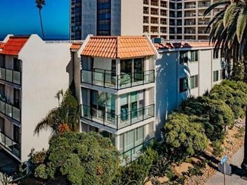 La Jolla apartment for rent - A building with a red tile roof is surrounded by green trees.