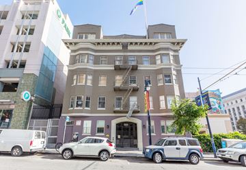 San Francisco apartment for rent - A building with a green sign on the front and a flag on top.