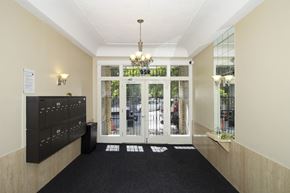 San Francisco apartment for rent - A hallway with a black carpet and a chandelier hanging from the ceiling.