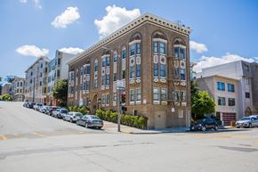 San Francisco apartment for rent - A street view of a row of buildings with cars parked on the side.