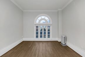 San Francisco apartment for rent - A room with a large arched window and wooden flooring.
