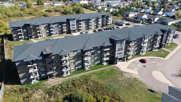 Moncton apartment for rent - Apartment complex with a red car parked in the driveway.