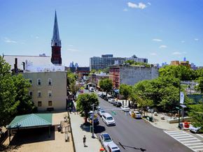 Queens apartment for rent - an aerial view of a city street with cars and a church tower