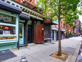 New York apartment for rent - a tree on a sidewalk in front of shops on a city street