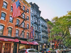 New York apartment for rent - a city street with buildings and cars and an flag
