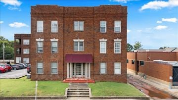 Tulsa apartment for rent - A red brick building with a red awning and a set of stairs leading up to the entrance.