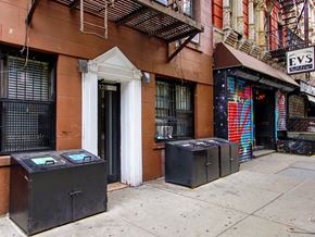 New York apartment for rent - the facade of a building with three boxes on the sidewalk