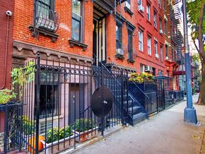 New York apartment for rent - A red brick building with a black iron fence in front.