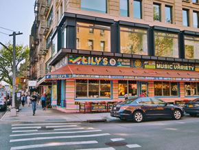New York apartment for rent - A black car is parked in front of a building with a red awning.