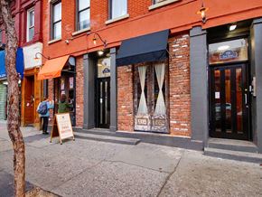 New York apartment for rent - the front of a brick building with a sign on the sidewalk
