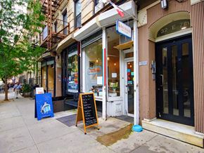 New York apartment for rent - a sidewalk in front of a store with a sign on the sidewalk