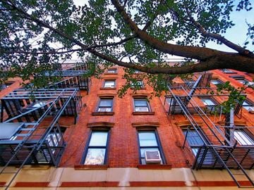 New York apartment for rent - a red brick building with fire escapes and a tree