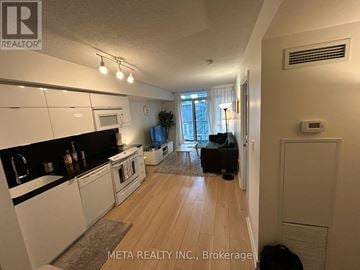 Toronto (Waterfront Communities) condo for rent - A well-lit kitchen with white cabinets and a dining area with a table and chairs.
