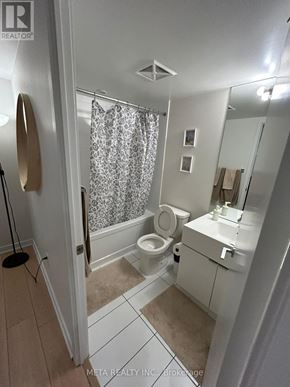 Toronto (Waterfront Communities) condo for rent - A bathroom with a toilet, sink, and shower curtain.