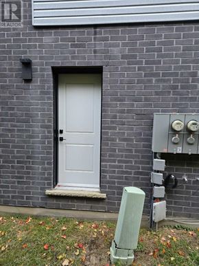 London South (South V) townhouse for rent - A grey door is on a brick wall with a grey electrical box and a green post in front of it.