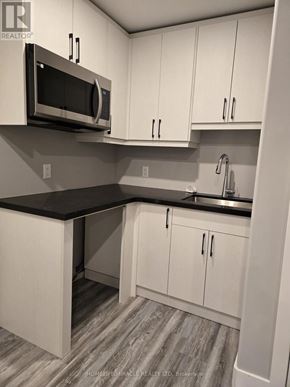 London South (South V) townhouse for rent - A kitchen with white cabinets and a black countertop.