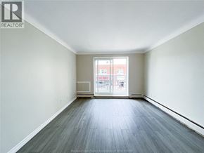 Windsor apartment for rent - A spacious room with a view of a building outside the window.