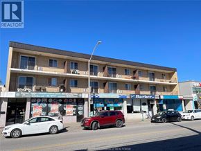 Windsor apartment for rent - A street view of a multi-story building with cars parked in front.