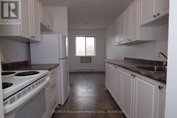 Brantford multi-family for rent - A kitchen with white cabinets and a white stove top oven.