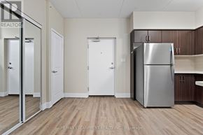 Hamilton (Durand) multi-family for rent - A kitchen with a refrigerator, wooden floors, and white walls.