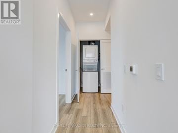 Waterloo condo for rent - A modern kitchen with white cabinets and a wooden floor.