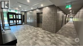 Kingsville condo for rent - A hallway with a tiled floor and a green exit sign above the door.