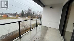Kingsville condo for rent - A balcony with a black railing and a view of a parking lot and trees.