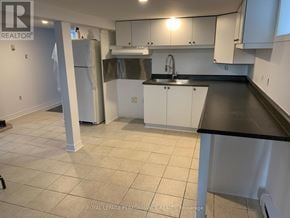 Casselman house for rent - A kitchen with white cabinets and a black countertop.