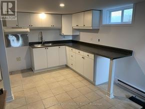 Casselman house for rent - A kitchen with white cabinets and a black countertop.