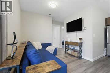 Hamilton condo for rent - A living room with a blue couch and a television mounted on the wall.