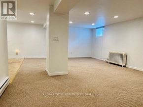 Toronto (High Park North) house for rent - A spacious room with a carpeted floor and a radiator on the wall.