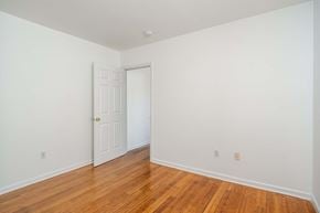 Jersey City apartment for rent - a bedroom with white walls and wood floors and a white door