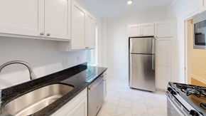 Brighton apartment for rent - a kitchen with white cabinets and a stainless steel refrigerator