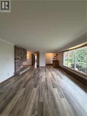 Stoney Creek house for rent - A spacious room with wooden flooring and a stone wall.