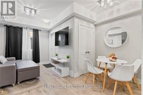 Niagara Falls (Arad/Fallsview) townhouse for rent - A modern living room with a grey sofa, a white dining table with chairs, and a television.