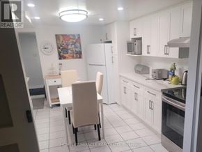 Oakville (Mo Morrison) house for rent - A kitchen with white cabinets and appliances, a clock on the wall, and a painting of a man and a woman.