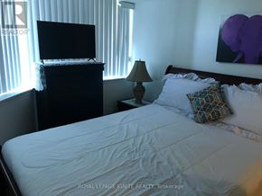 Toronto (Rouge) condo for rent - A bedroom with a bed, a television, and a lamp.