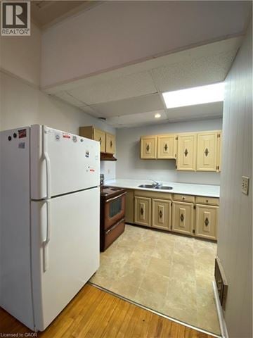 Paris apartment for rent - A kitchen with a white refrigerator and wooden cabinets.