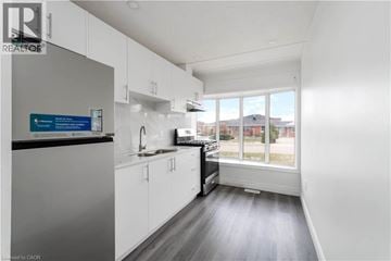 Stoney Creek house for rent - A kitchen with white cabinets and a black countertop.