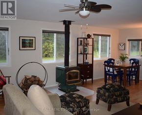 North Kawartha house for rent - A living room with a wood stove and a fan.