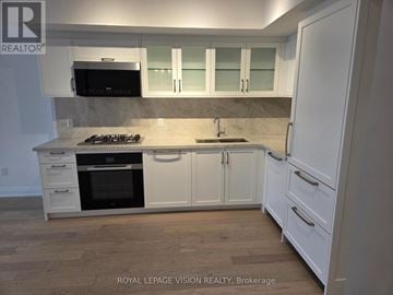 Toronto (Englemount-Lawrence) condo for rent - A kitchen with white cabinets and a black stove top oven.
