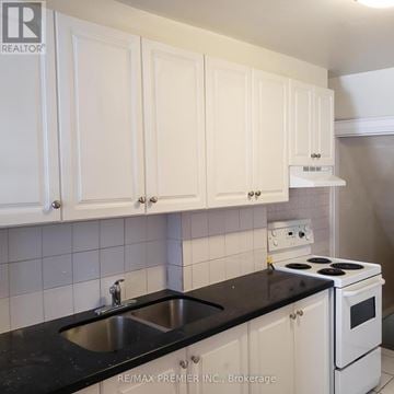 Toronto (Oakwood Village) house for rent - A kitchen with white cabinets and black countertops.