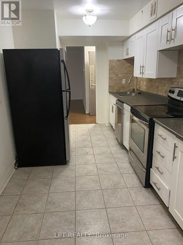 Markham (Royal Orchard) condo for rent - A kitchen with black appliances and white cabinets.
