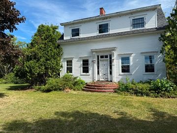 Fredericton apartment for rent - A white house with a red door and a brick staircase leading to it.