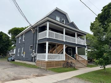 Fredericton apartment for rent - A two-story house with a grey exterior and white railings.